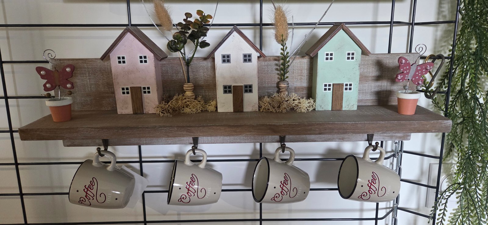 Détail de l'étagère murale esprit village et café : maisons en bois, pinces mémo et tasses en céramique